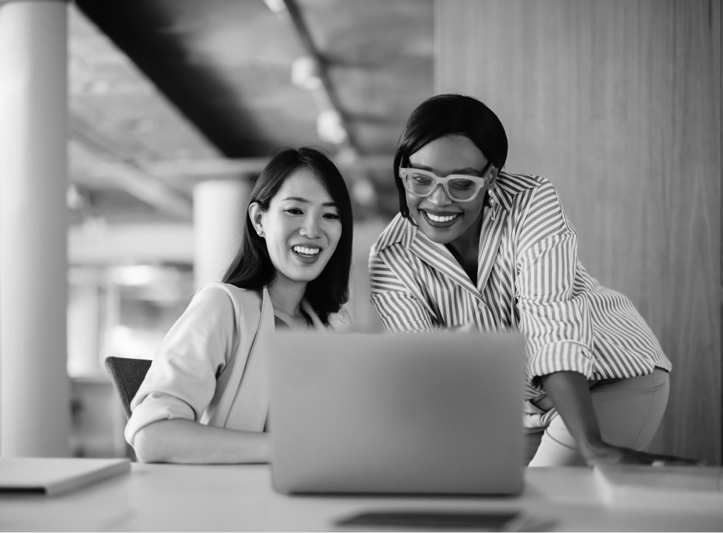 Two colleagues looking at a laptop together.